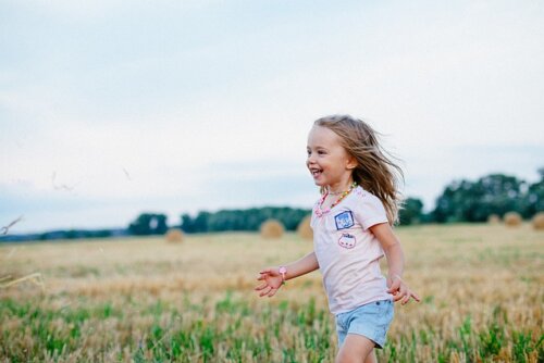 Little girl laughing and walking in a flower field